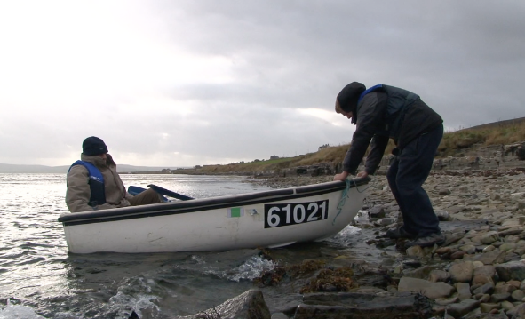 man pushing a rowing boat off shore